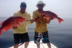two men holding large redfish