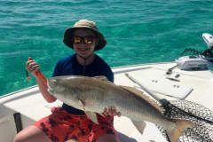 young boy, sitting on a boat, holding a large fish