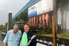 two men in front of their redfish catch at the living right fishing charters cleaning station