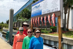 group of four next to their redfish catch
