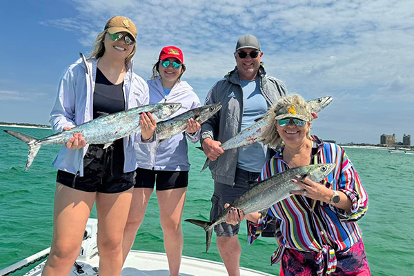 a group of four adults all holding a large fish